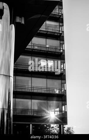Monotone low angle view looking up at modern high rise building with sun flare Stock Photo