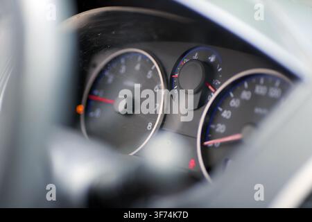 Car dashboard displaying a tachometer, speedometer, fuel gauge, and engine temperature indicator, with warning lights illuminating the instrument pane Stock Photo