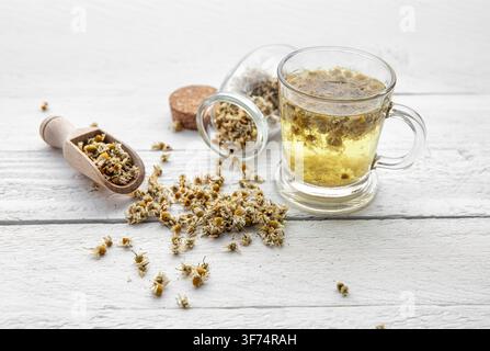 Matricaria chamomilla, commonly known as chamomile, wild chamomile or scented mayweed herbal tea in glass. Organic dried herbal tea powder. Stock Photo