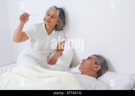 Wife checking husband's fever Stock Photo