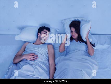 Angry woman looking at man snoring Stock Photo