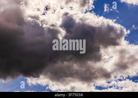 Close-up view of dramatic dark storm clouds gathering across blue sky in changing weather. Stock Photo