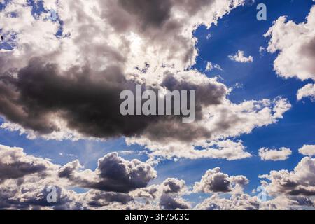 Beautiful view of dramatic cumulus clouds against deep blue sky with sunlight breaking through. Stock Photo