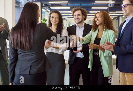 Diverse business team cheering handshake during office meeting, welcoming partner Stock Photo