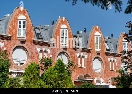 Repeating curved brick gables and circular windows on an elegant sunlit residential building Stock Photo