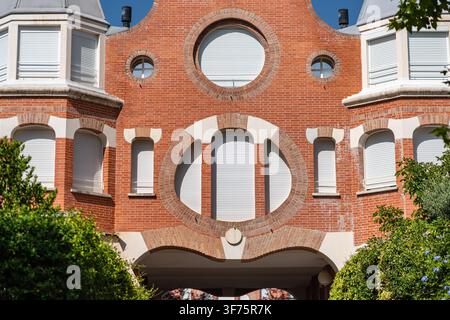 Symmetrical red brick facade with circular windows arched masonry and white window shutters Stock Photo