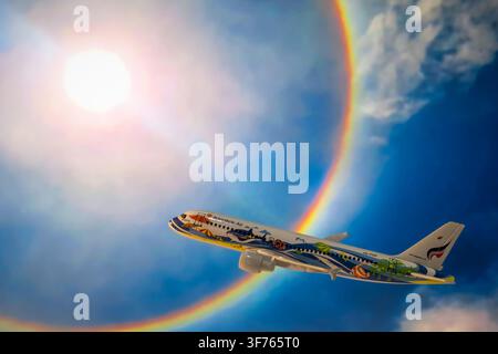 Chiang Mai, Thailand - 07 August 2026 : Bangkok Airways whale shark livery scale model airplane flying against solar halo rainbow sky background Stock Photo