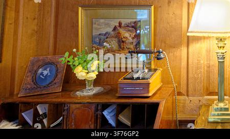 An antique multi-line intercom console telephone with a black handset sits on a wooden rolltop desk inside Castle Drogo, Devon, England, on 25.08.2024 Stock Photo