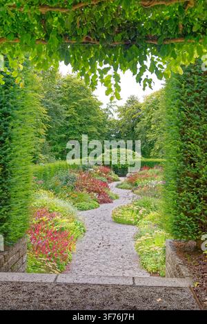Winding gravel pathway curving through a vibrant herbaceous perennial border and manicured hedges at Castle Drogo in Devon, shot on 25.08.2024. Stock Photo
