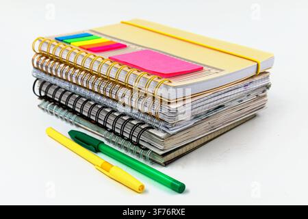 Stack of spiral notebooks with colorful pens and sticky page markers for studying Stock Photo
