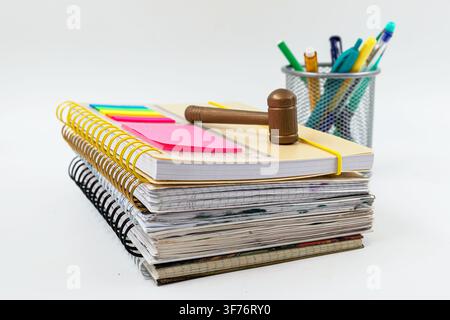Wooden gavel resting on spiral notebooks with colorful school stationery and notes Stock Photo