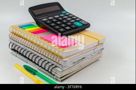 Calculator on stacked spiral notebooks with colorful stationery for mathematics study Stock Photo