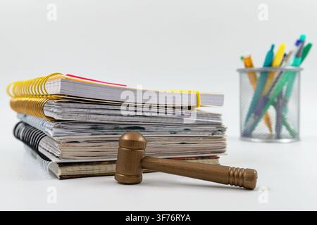 Wooden gavel resting on spiral notebooks with colorful school stationery and notes Stock Photo