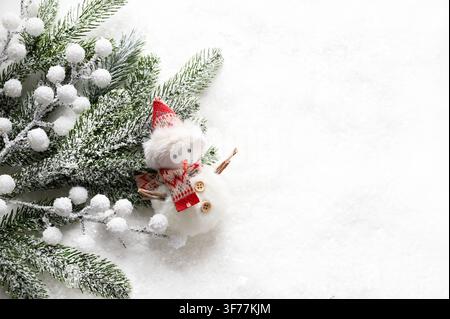 Small plush snowman ornament with snowy pine branches on white background. Flat lay holiday composition with copy space. Christmas and holiday concept Stock Photo