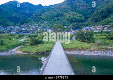 Narrow bridge with no railing to countryside village on river in Shikoku, Japan Stock Photo