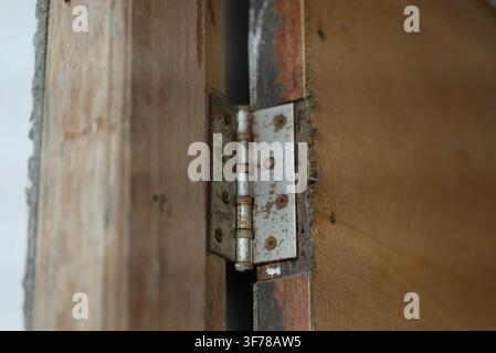 Rusty wooden door hinge. Vintage rusty door hinge on textured old wood Stock Photo