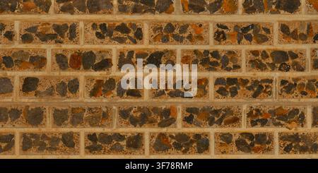 A close-up view of a brick wall constructed with dark exposed aggregate stone inlay. Stock Photo