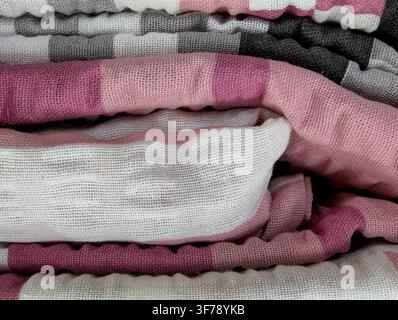 A close-up top-down view of neatly stacked pink and white fabric rolls in an indoor setting, possibly a textile store or workshop. The neutral mood co Stock Photo