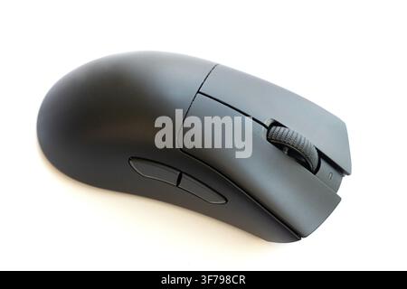A modern black computer mouse sits on a white surface Stock Photo