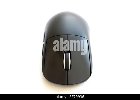 A modern black computer mouse sits on a white surface Stock Photo