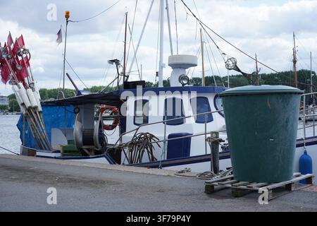 Travemünde, Germany - August 8, 2026: Small fishing boat moored at the quay on the Trave river with fishing gear and flag markers, Lübeck. Stock Photo