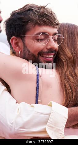 Two friends hugging outdoors during a social gathering. Stock Photo