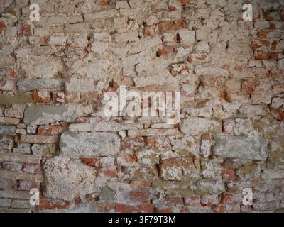 Old Weathered Brick and Stone Wall Texture with Peeling Plaster, Grunge Rustic Background for Design, Architecture and Construction Projects. A close- Stock Photo