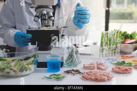 Scientists in lab coats work with plants in a modern lab, focusing on research and experimentation under bright, sterile conditions. Stock Photo