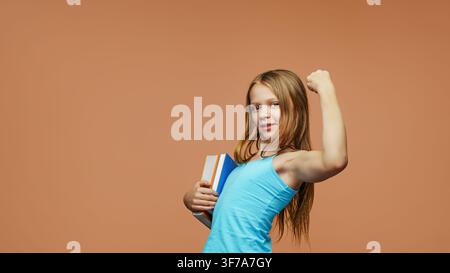 A happy schoolgirl with a books stands on an isolated background. Back to school and joy of learning concept. Stock Photo