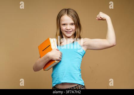 A happy schoolgirl with a books stands on an isolated background. Back to school and joy of learning concept. Stock Photo