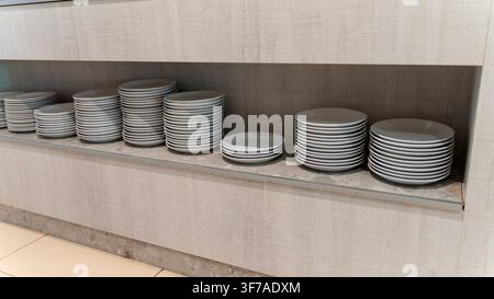 Stacks of White Ceramic Plates on Shelf in Restaurant Buffet Area Stock Photo