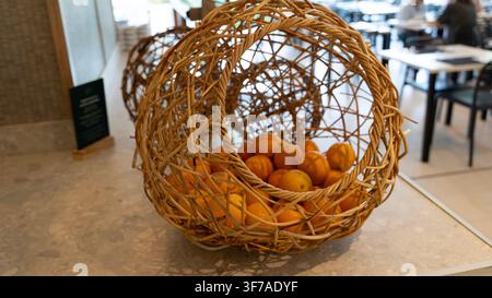 Wicker Basket with Fresh Oranges on Table in Restaurant Interior Stock Photo