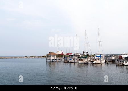 Serene marina featuring sailboats and yachts docked beside a waterfront pier with calm water at Petoskey, Michigan Stock Photo