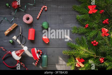 Overhead Christmas composition featuring evergreen branches colorful ornaments candy canes ribbon and festive decorations arranged on a dark wooden ba Stock Photo