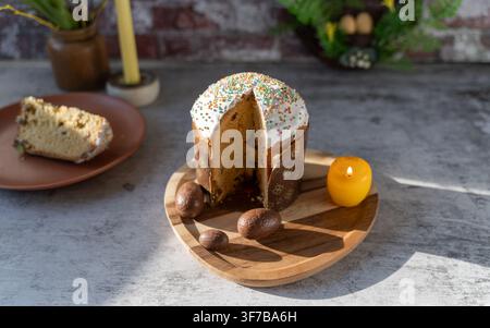 Traditional Eastern European Paska also known as Pasca displayed on a wooden serving board with a slice removed and surrounded by tulips greenery and Stock Photo