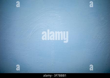 Soft blue wall with subtle textured surface. Smooth finish shows gentle brush strokes and slight imperfections. Ideal background for minimalist or ser Stock Photo