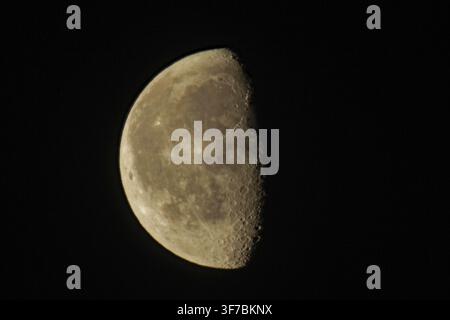 Moon half illuminated against dark evening sky, Buchhofen, Bavaria, Germany Stock Photo
