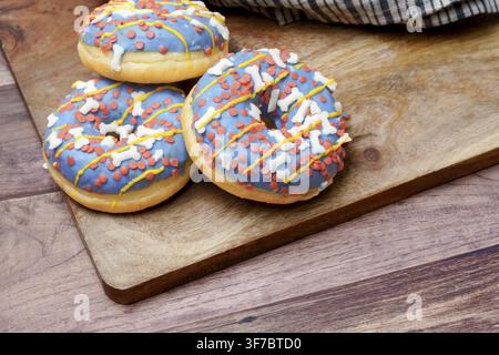 Three sweet blue donuts with colorful sprinkles and white bone shapes on a wooden board Stock Photo