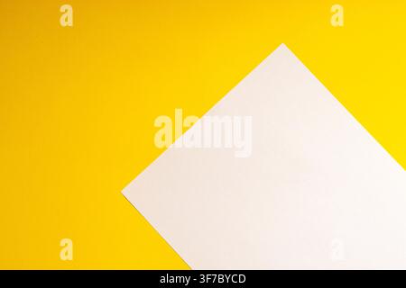 A blank sheet of paper is placed on a bright yellow table. The scene shows preparation for the new school year. This area feels lively and ready for l Stock Photo