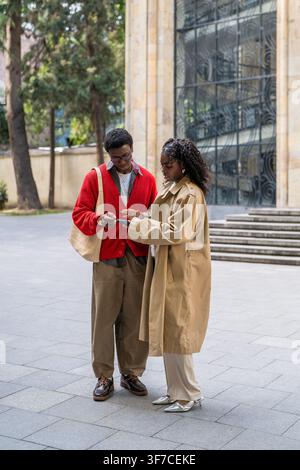 Couple of african american friends man and woman exchanging phone numbers while meeting in city. Stock Photo