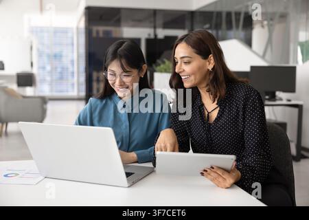 Two multiethnic women working together using laptop and tablet Stock Photo