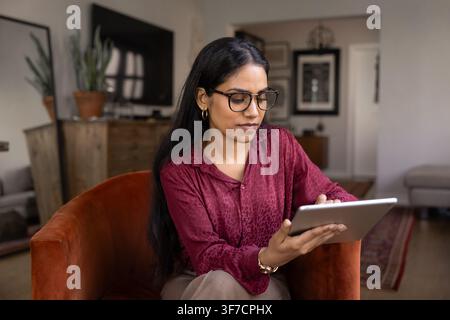 Young 25s Indian woman using digital tablet at home Stock Photo