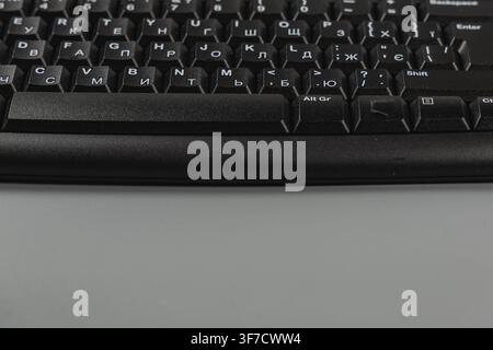 A black keyboard sits on a white desk in an office. This space is set up for digital work with a mouse nearby. Stock Photo