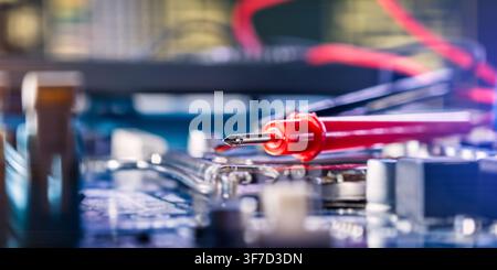 Macro view of a multimeter probe testing a printed circuit board. High-tech electronics maintenance. Stock Photo
