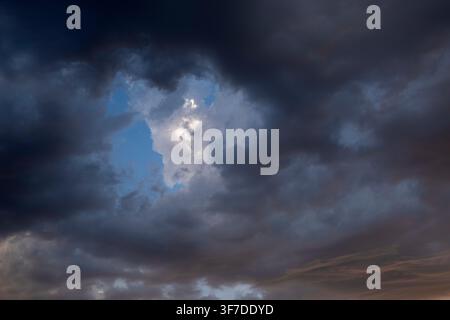 Dramatic storm clouds with blue sky and sunlight breaking through Stock Photo