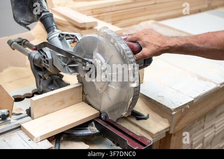 Worker using circular miter saw to cut wooden plank Stock Photo