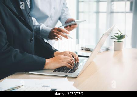 Business professional typing on laptop with tablet and financial documents on office desk, showing digital accounting work, online report review and p Stock Photo