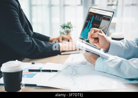 Business team analyzing financial dashboard on digital tablet with charts and documents in modern office, showing data analytics, investment planning Stock Photo