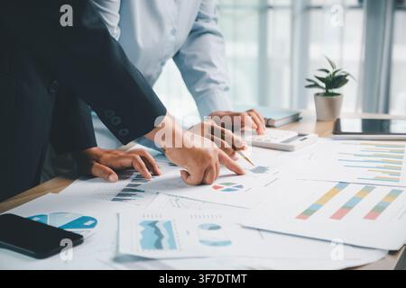 Business team pointing at financial charts and calculator during office meeting, representing accounting analysis, sales report review and budget plan Stock Photo