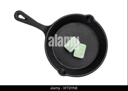 Dishwasher detergent tablets inside cast iron pan on dark background creative metaphor of cleaning versus cooking concept. Stock Photo